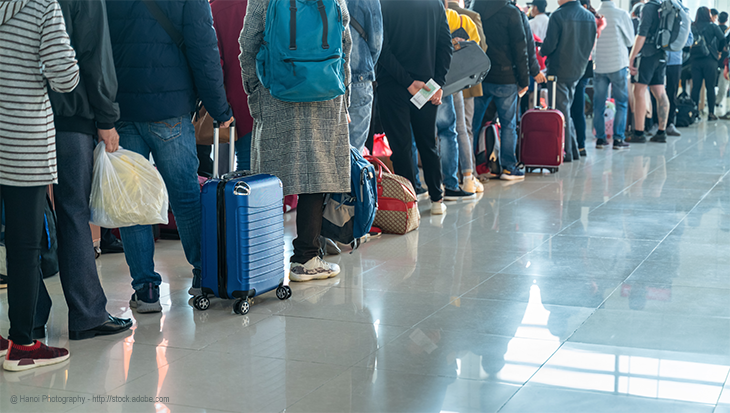 People waiting in line at the airport with their luggage.