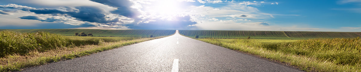 Image of a paved highway extending out toward a horizon line.